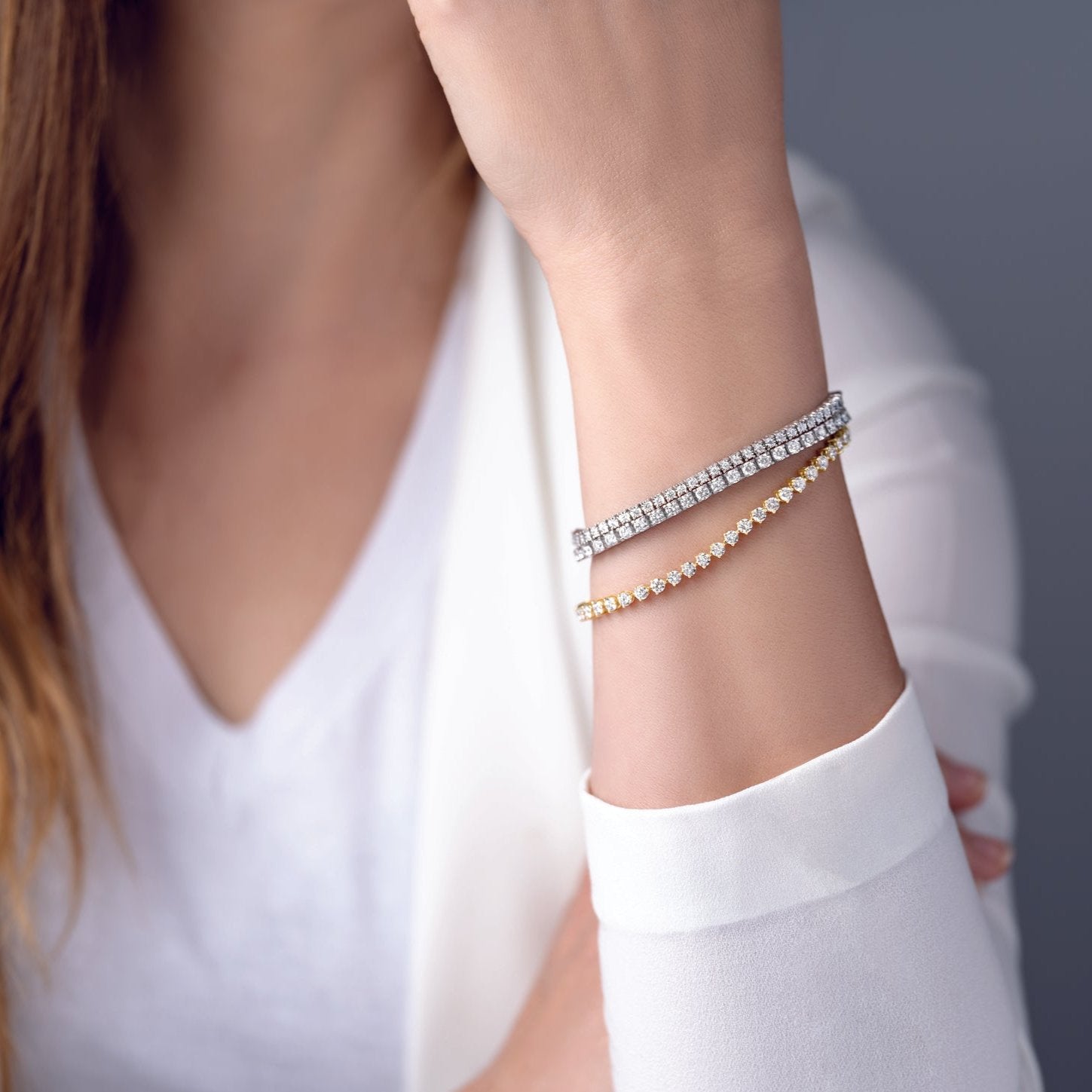 Close-up of a wrist adorned with eco-friendly, lab-grown diamond tennis bracelets in gold and platinum, showcasing sustainable luxury from JLab Jewelry.